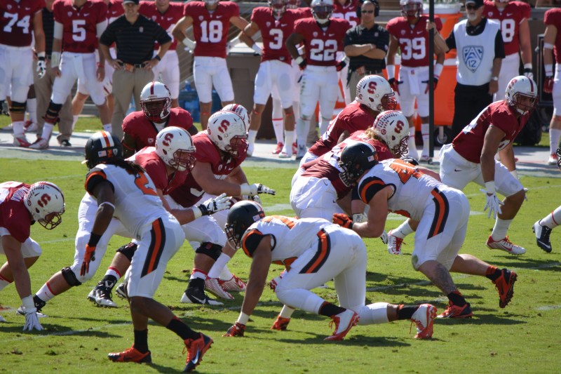 Stanford and Oregon State linemen rush at each other during a football game