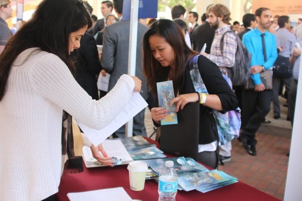 People stand at a career recruiting booth.