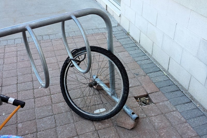 a lone bike wheel locked to a bike rack
