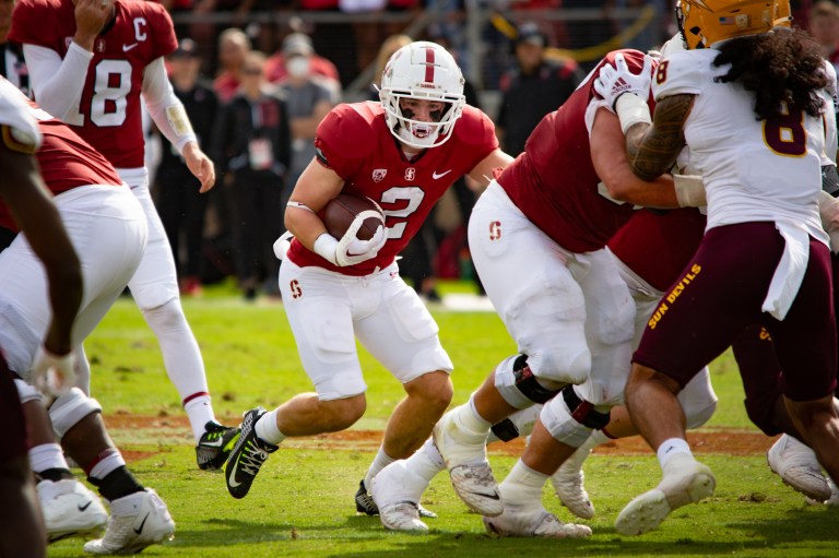 A running back runs the football between his offensive linemen