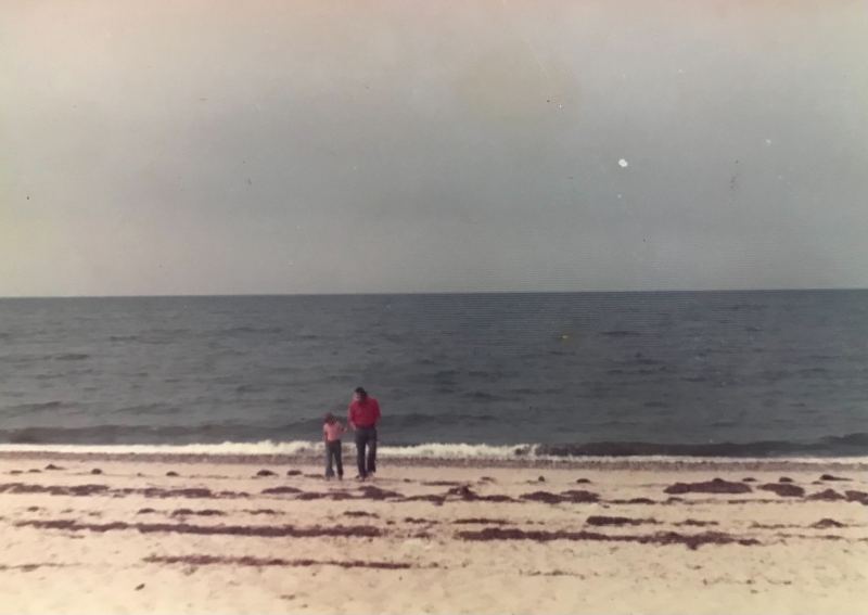 A child and adult on a beach.