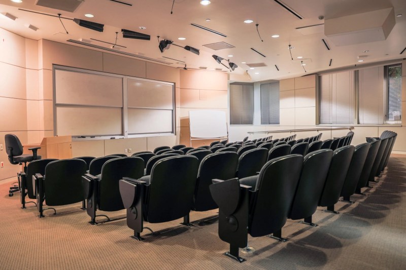 an empty classroom with auditorium style seating and stacked whiteboards at the front