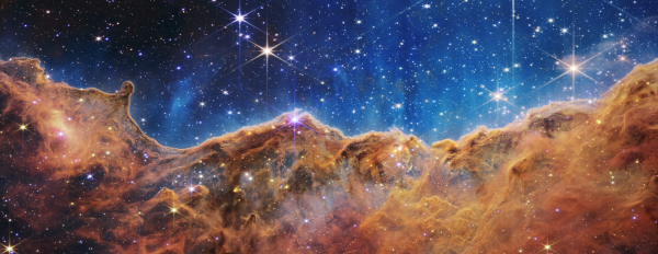 Image captured by the James Webb telescope. As NASA describes, it is "a landscape of “mountains” and “valleys” speckled with glittering stars is actually the edge of a nearby, young, star-forming region called NGC 3324 in the Carina Nebula."