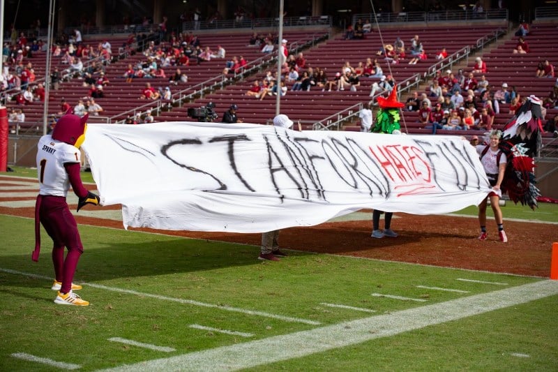 White banner reading 'STANFORD HATES FUN' in black and red capital letters on football field at Stanford/ASU Game.