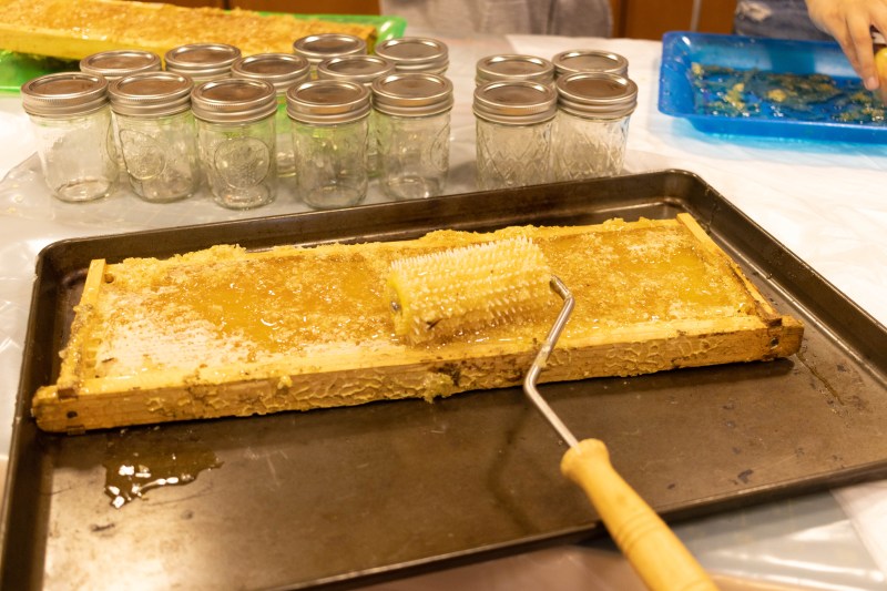 Honey comb roller on top of honey comb tray, with small glass jars in the background.