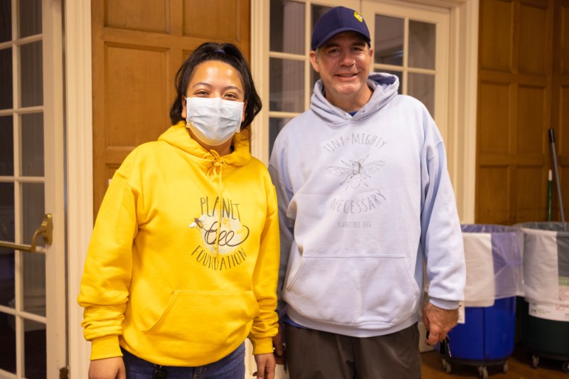 Shelia Afnan wearing a yellow hoodie saying 'Planet Bee Foundation' on the left and Jason Graham wearing a pale blue hoodie saying 'Tiny-Mighty Necessary' on the left.