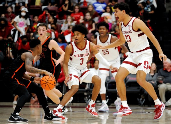 Three Stanford basketball players look at a player in a black uniform