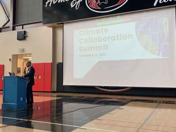 Person stands at podium in front of screen reading "Climate Collaboration Summit"