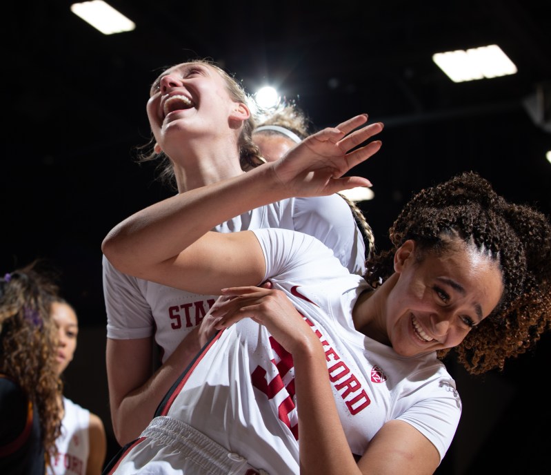 Two female basketball players smile after bumping in celebration