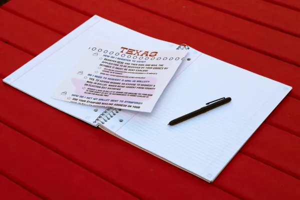 A ballot that says "texas" at the top on a red table with a pen next to it