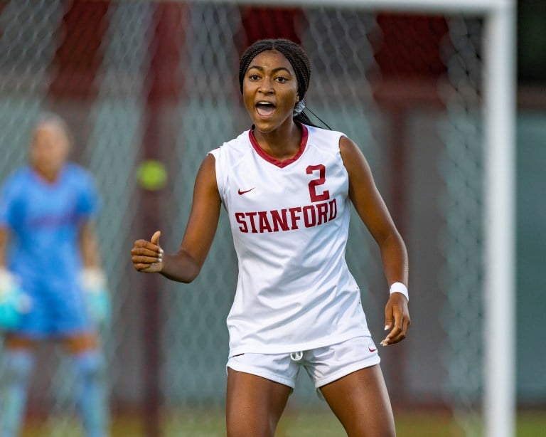 A soccer player in a white jersey yells out