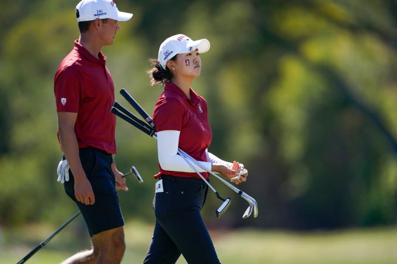 Two golfers, a female on the right and male on the left, stand side-by-side