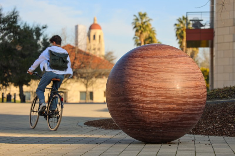 Someone bikes past a planetary orb in the Engineering Quad.