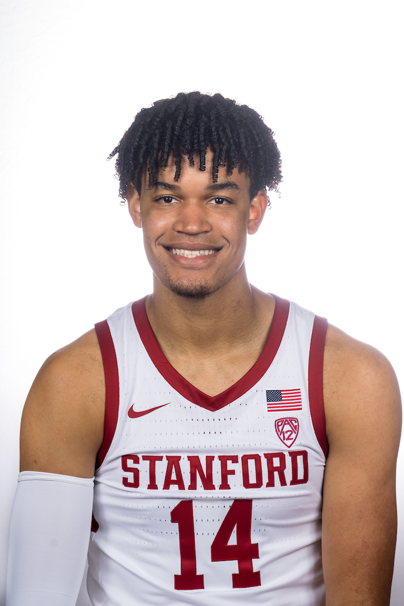 Spencer Jones, a basketball player wearing a white "Stanford" basketball jersey with #14, smiles