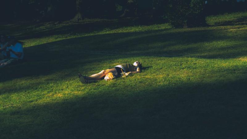 Person lying on an expanse of grass in the sun.