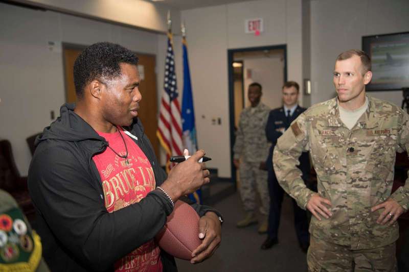 Herschel Walker posing with a National Guardsman and a signed football