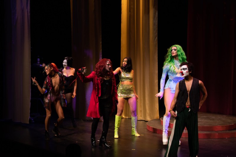 A photo of six performers in the drag show strutting across the stage.