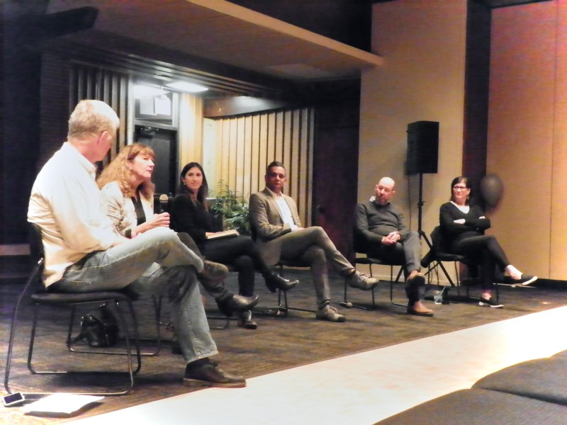 A photo of six panelists sitting on stage in a half circle and engaged in discussion.