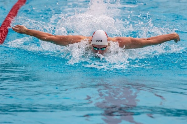 A swimmer emerges from the water mid-stroke