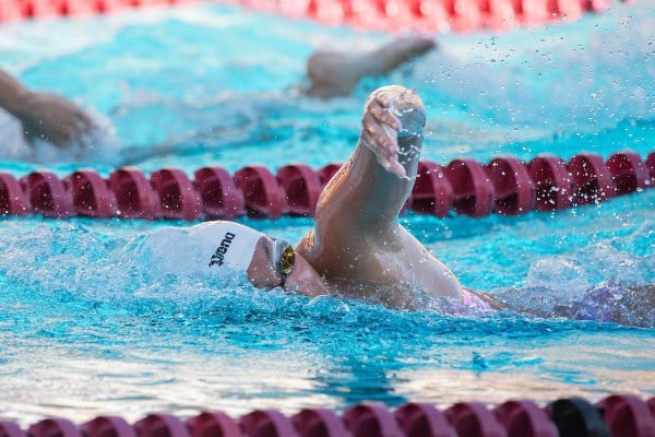 A female swimmer emerges from the water