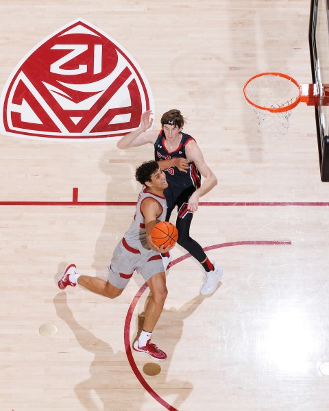 A basketball player goes up for a layup with a defender at his side