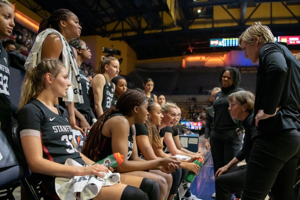A basketball team looks at their coach while seated on the bench