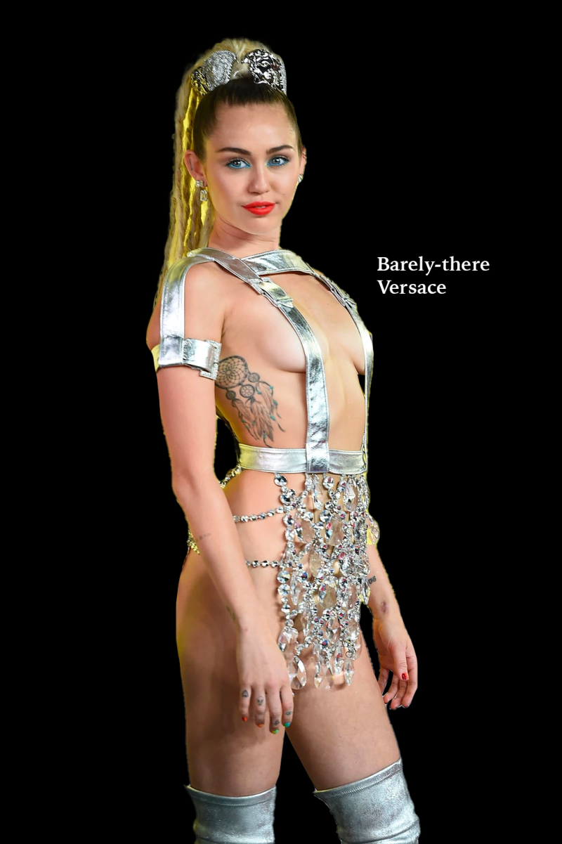 a photo of a white person wearing a barely-there silver dress consisting of some straps over the torso and dangling gemstones over the groin. the person's hair is styled in long blonde locs.
