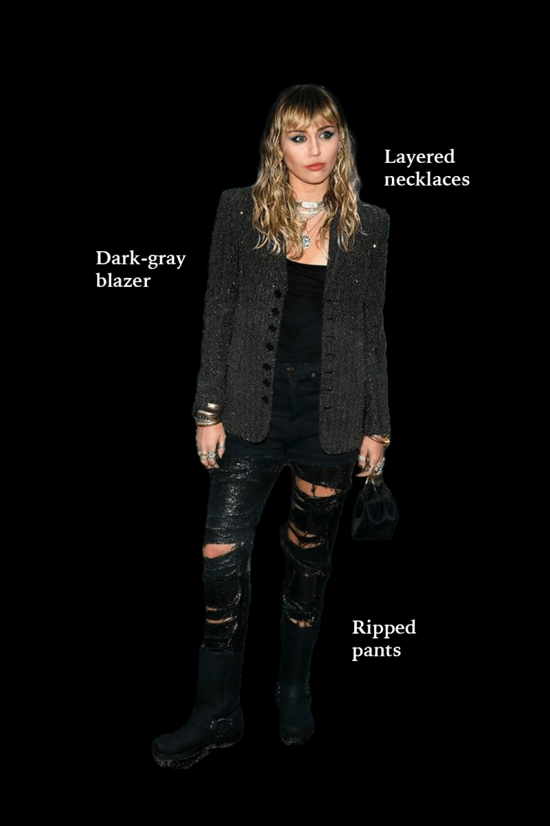 a photo of a blonde white person wearing a sparkly black blazer over a black tank top, ripped black pants and layered silver necklaces.