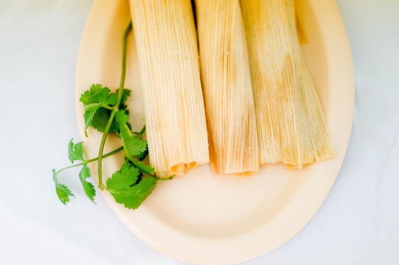 Three tamales—a Mexican dish—on a plate