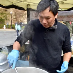 Anson Lin stands over a steaming pot, holding tongs.