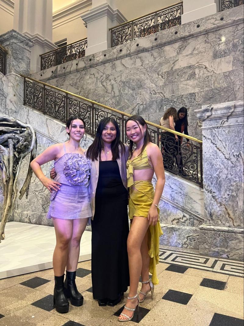 Catherine Sarca stands between two student models, Valeria Gonzalez and Stephanie Unur wearing Sarca's own designs. 