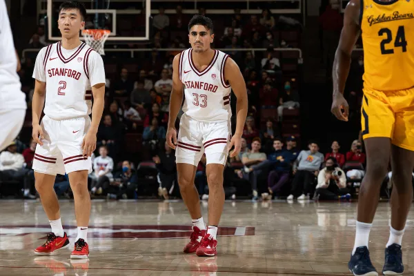 Two Stanford basketball players in a ready stance on the basketball court