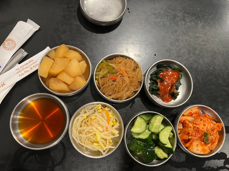Seven small metal bowls contain various toppings.