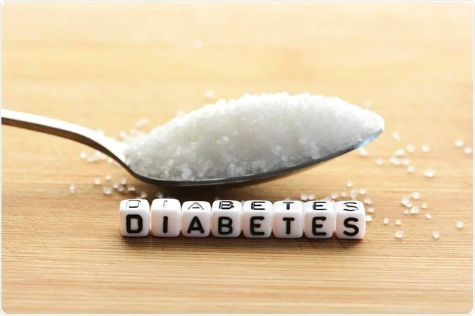 A spoon of white sugar, next to a line of letter blocks spelling "diabetes."