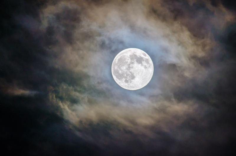 The full moon behind thin clouds.