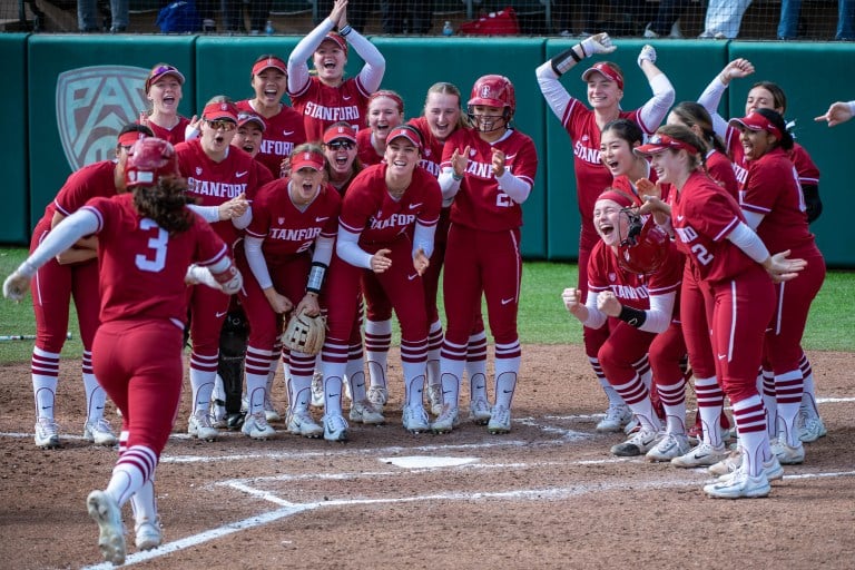 Players celebrate in a semi-circle during a softball game.