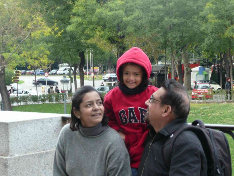A young girl in a red hoodie with her grandparents in a park.