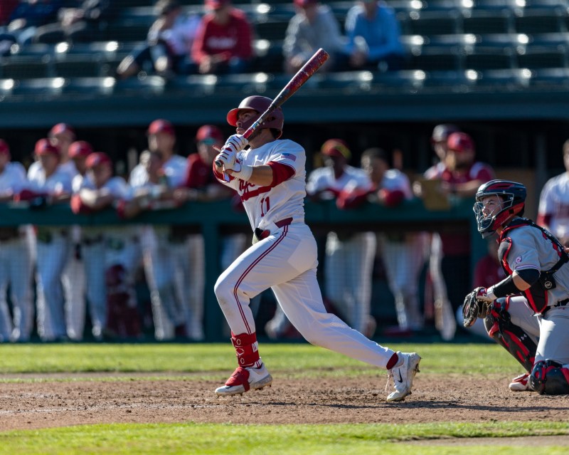 A batter looks at a baseball after hitting it, post swing. 
