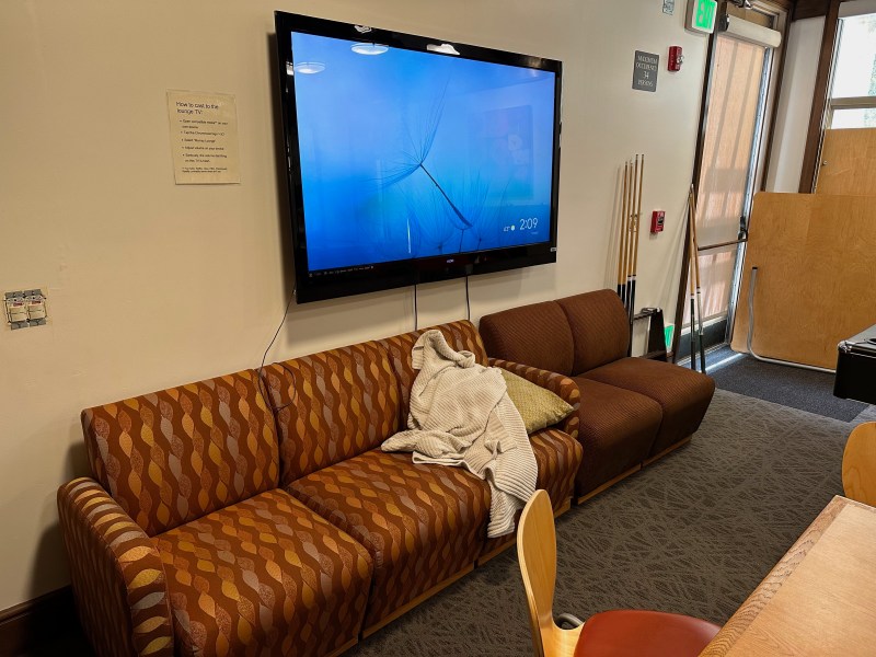 A couch with a blanket on it and a TV in the background