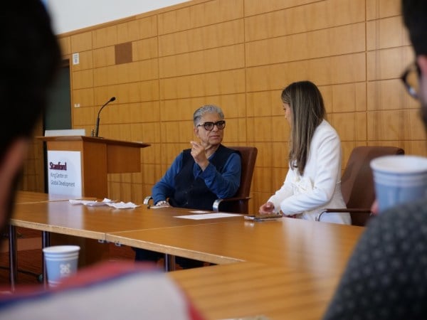 Deepak Chopra (left) and Sophia Kianni (right) seated at a table next to a podium, which reads "Stanford King Center for Global Development"