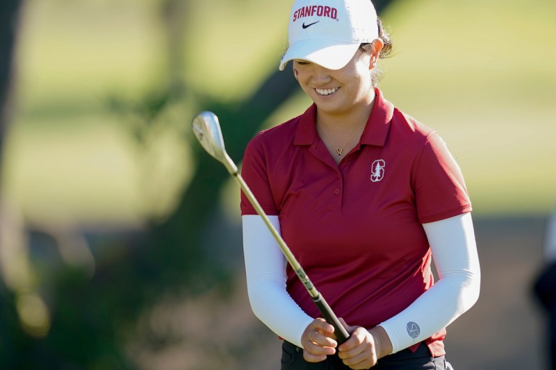 A Stanford womens golfer looks at her club while on the course