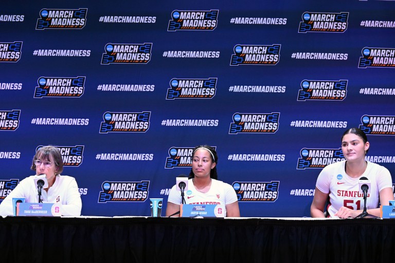 Coach Tara VanDerveer and players Lauren Betts and Indya Nivar sit on a podium addressing the media