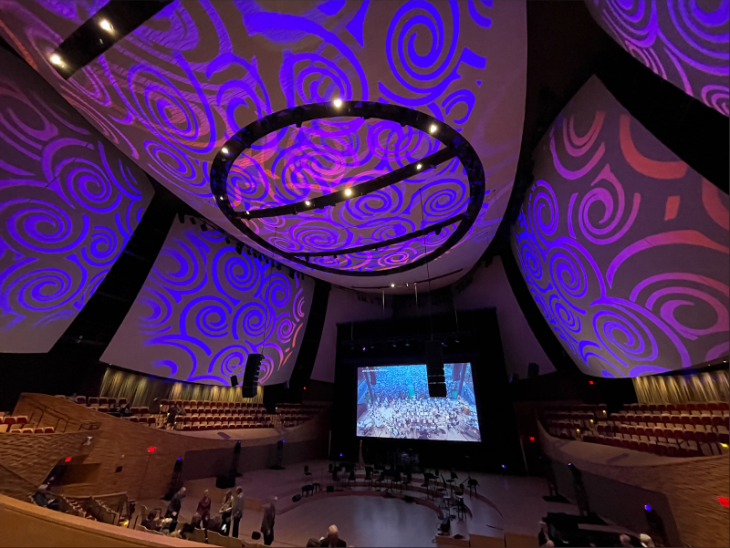 Ceiling of the Bing Concert Hall with projected purple colored swirls and a big screen on the stage