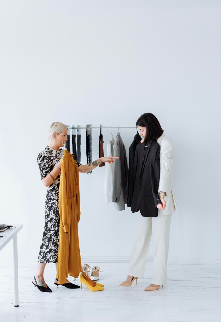 Two women of different ages and a rack of clothes behind them