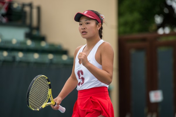 Tennis player Valencia Xu, dressed in Stanford colors, celebrates with a clenched fist during a tennis match.