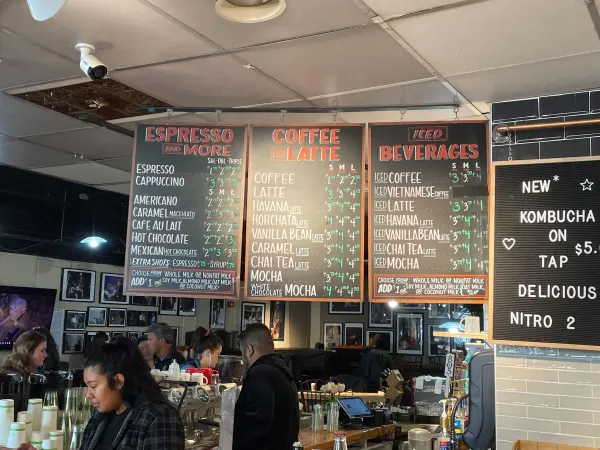The CoHo menu hangs above workers and customers displaying their food and drink options.