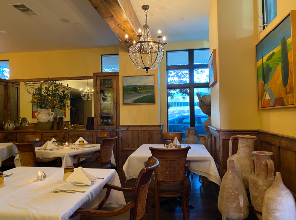 The inside of Caffe Riace displays white tablecloths, a chandelier and wooden chairs.