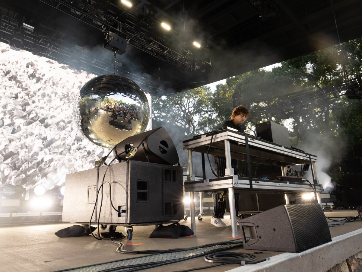 An artist played on a large keyboard. In the background is a large silver disco ball.