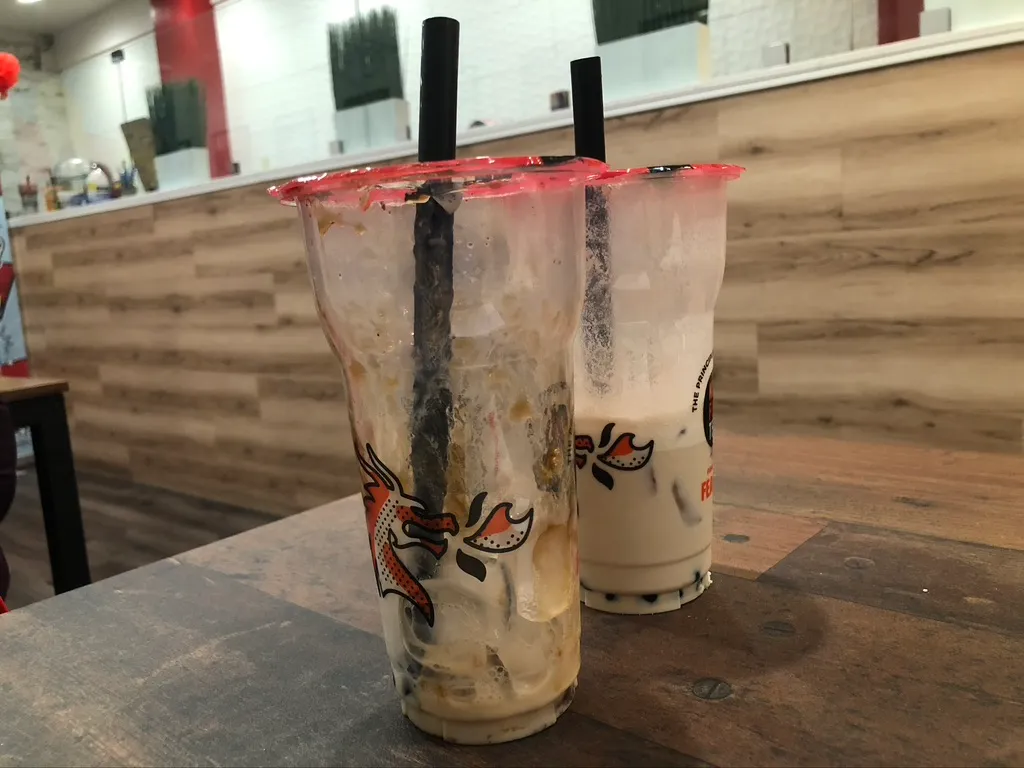 Two boba drinks from Kung Fu Tea cafe sit half-finshed next to each other.