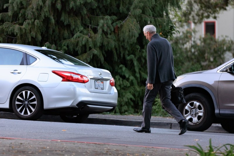 Stanford's president walks next to a car